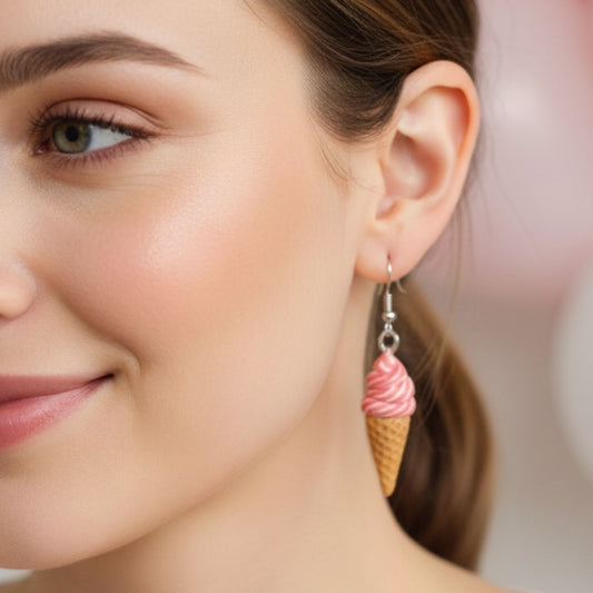 Close-up of a woman wearing pink swirl ice cream shaped dangle earrings with a blurred background.