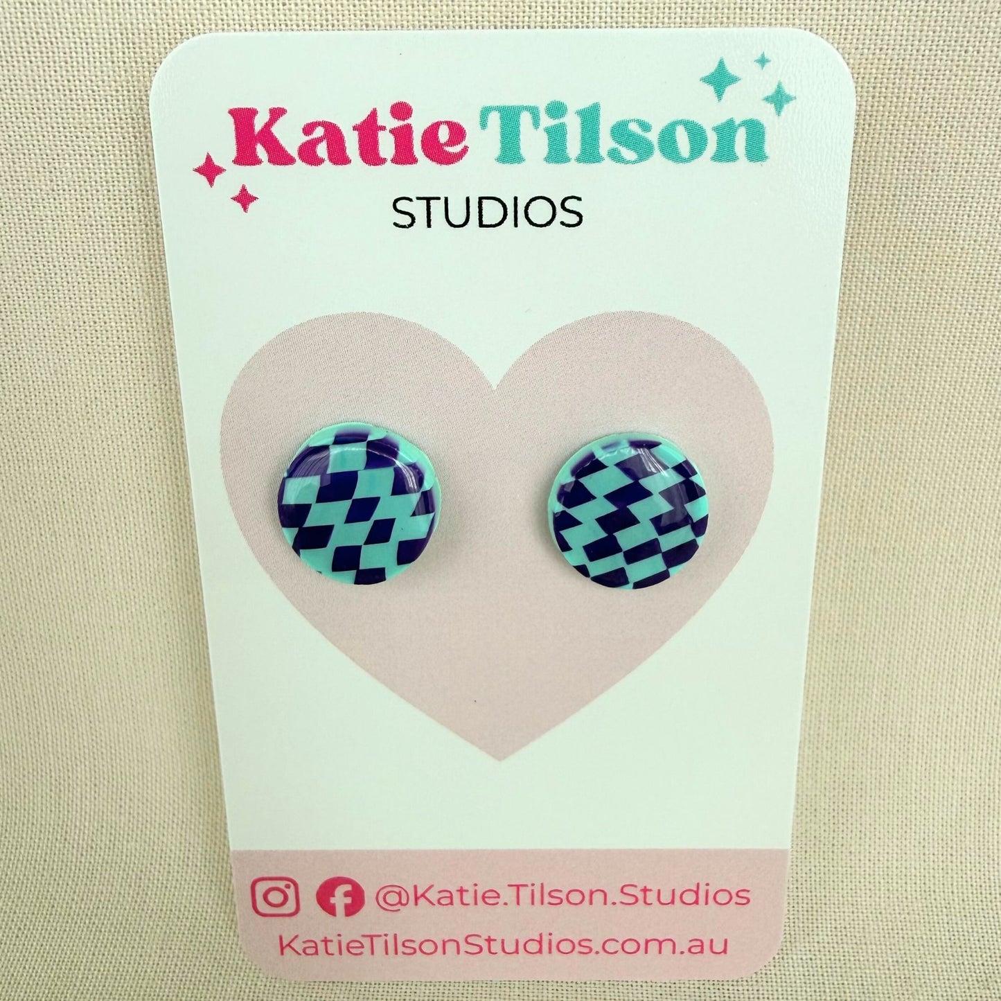 Pair of mint and violet check stud earrings on a Katie Tilson Studios earring card.