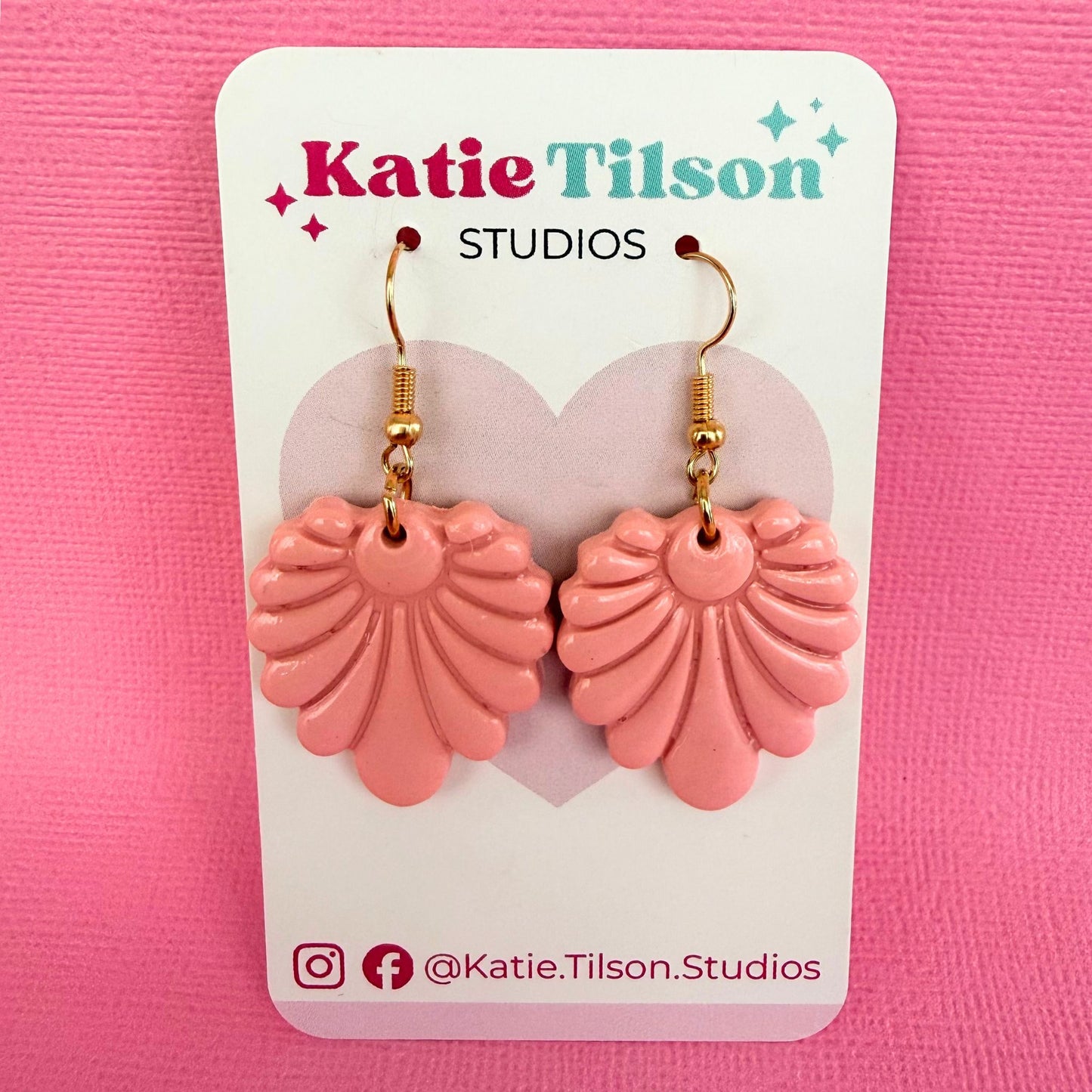Pink fan shaped dangle earrings with gold hooks on a Katie Tilson Studios card against a pink background.