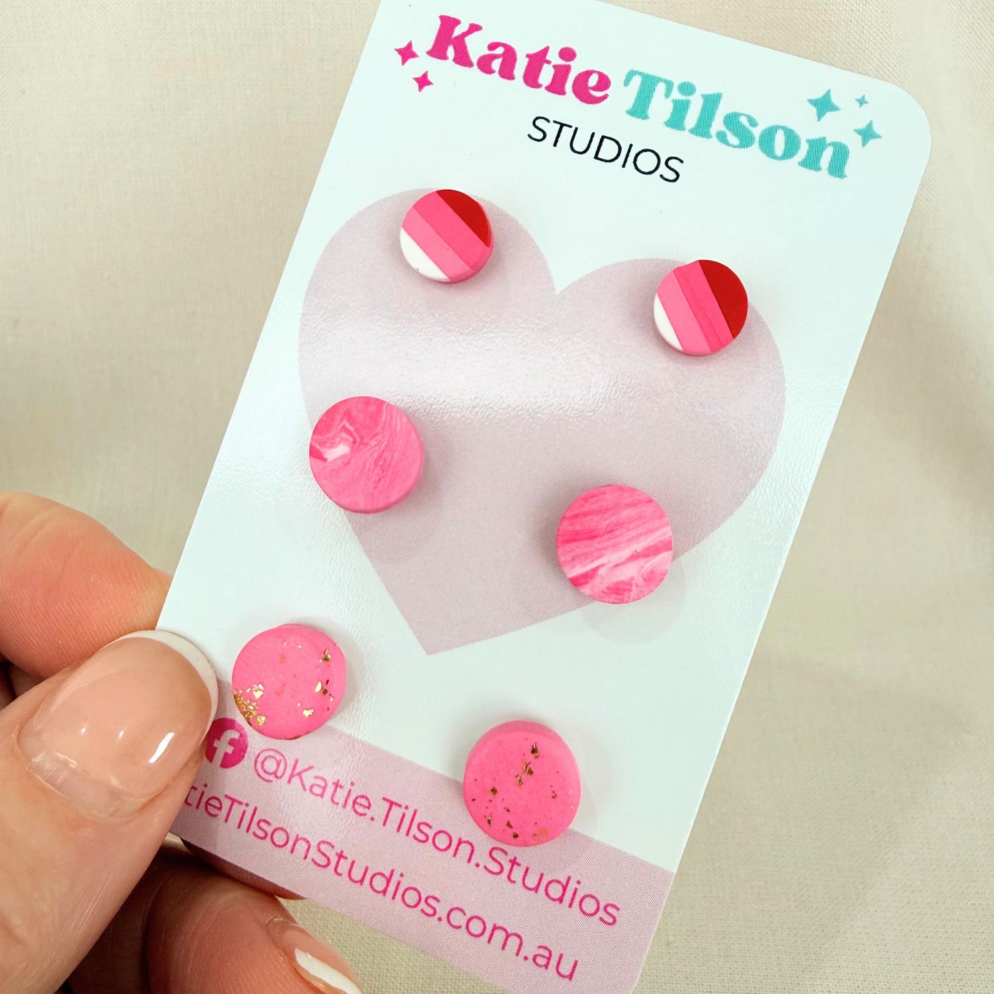 Australian handmade stud earrings trio Sweet Little Things in pink design on a Katie Tilson Studios branded earring card against a beige background.