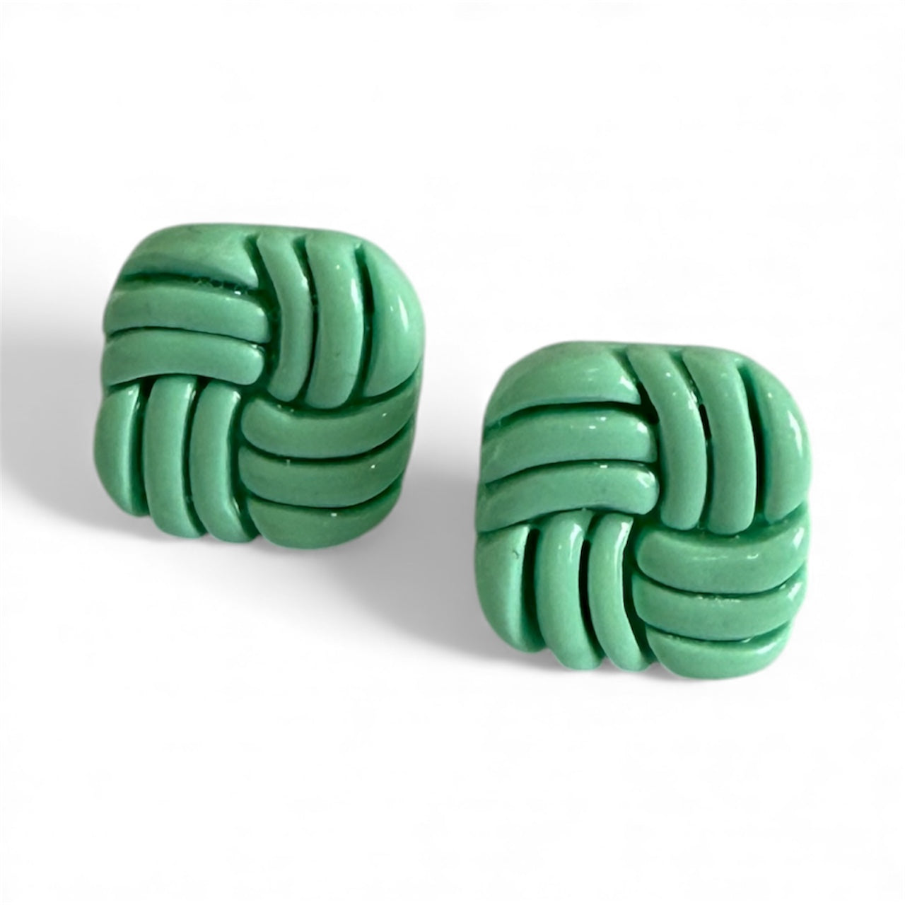 mint green polymer clay stud earrings in a knot design on a white background