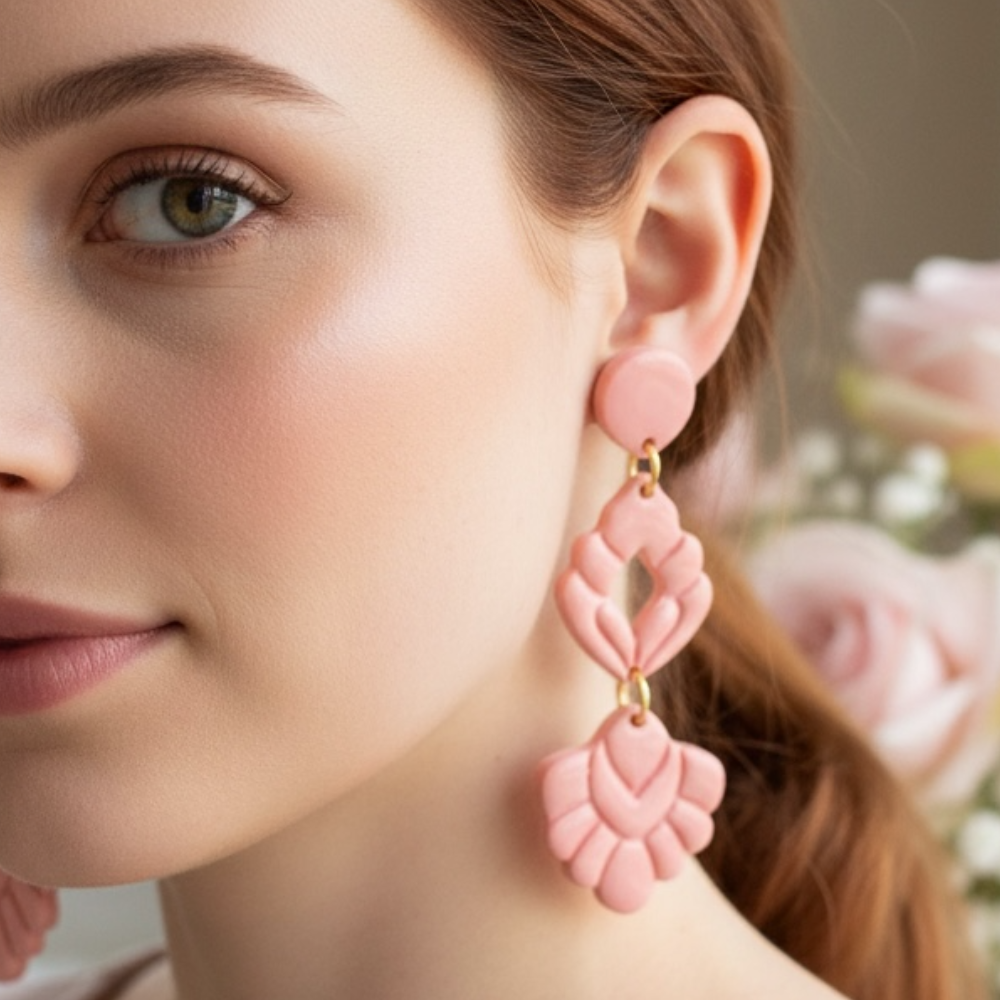 Close-up of a woman wearing pink statement earrings with a blurred floral background.