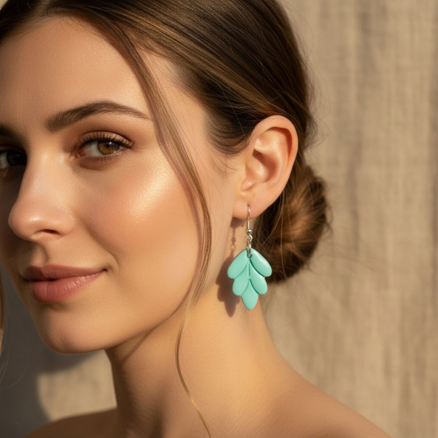 Aqua Leaf handmade dangle earrings in aqua with silver findings worn on woman's ear to show details.