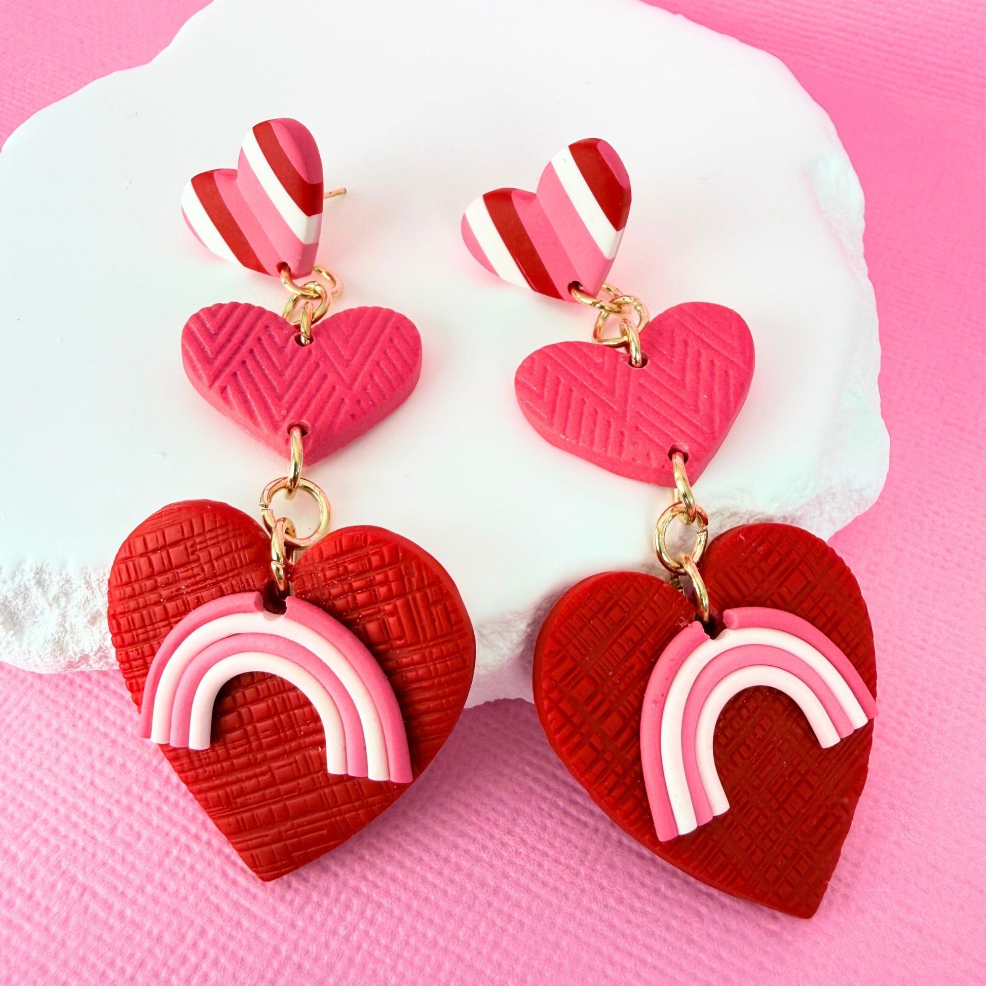 Head Over Heels Hearts handmade statement earrings in a drop style with a tiered heart shaped design in pink, red and white.