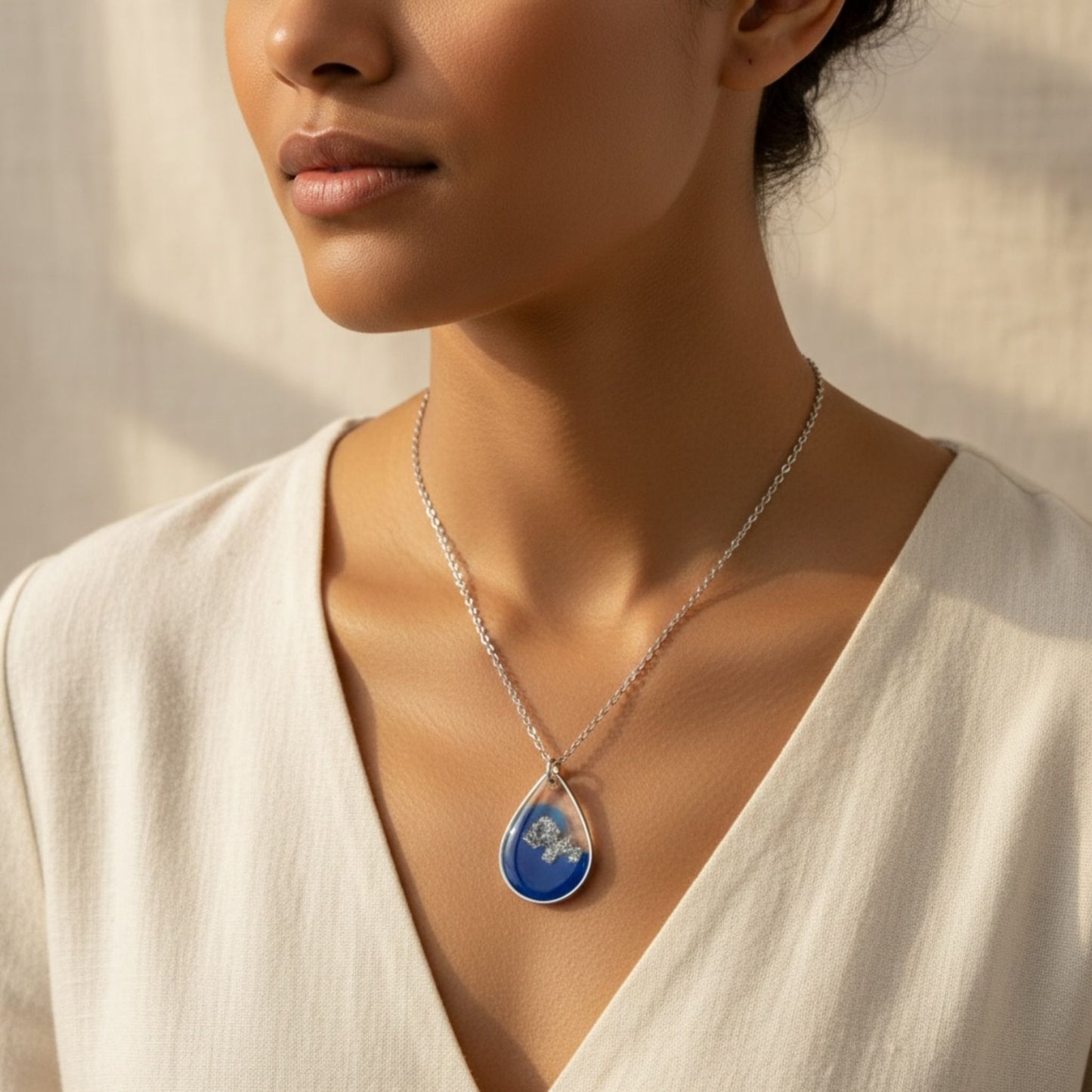Woman wearing Azure Veil Australian handmade necklace in soft blue resin and silver shimmer by Katie Tilson Studios