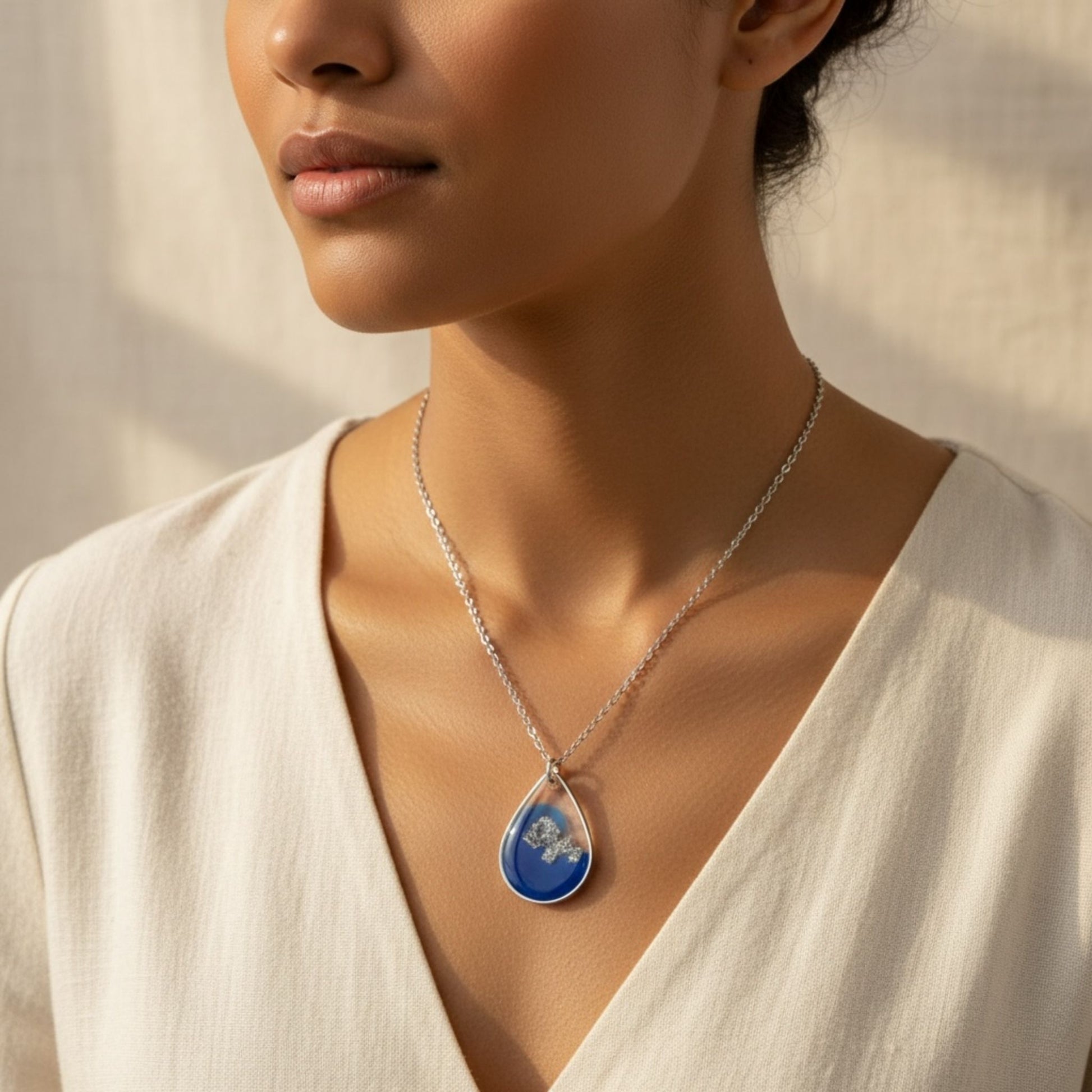 Woman wearing Azure Veil Australian handmade necklace in soft blue resin and silver shimmer by Katie Tilson Studios