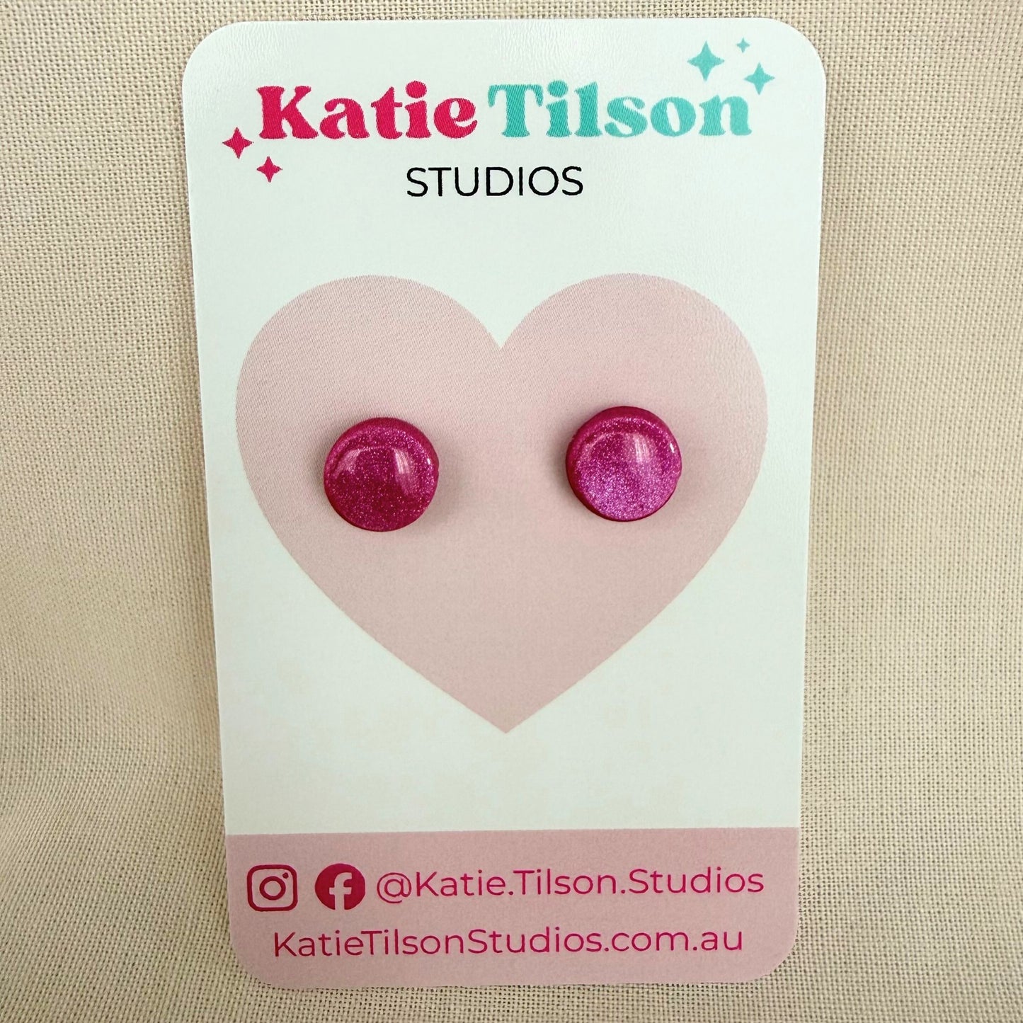 Berry coloured round stud earrings on a Katie Tilson Studios card against a beige background.
