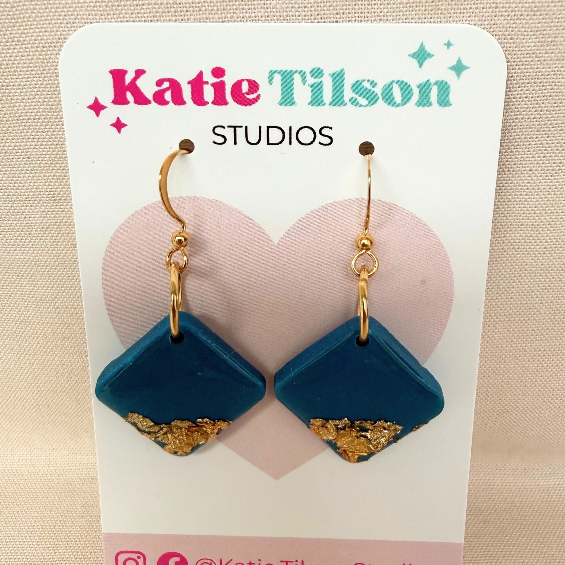 Bright Side Australian handmade teal dangle earrings in diamond shape with gold leaf detail on a branded earring card.