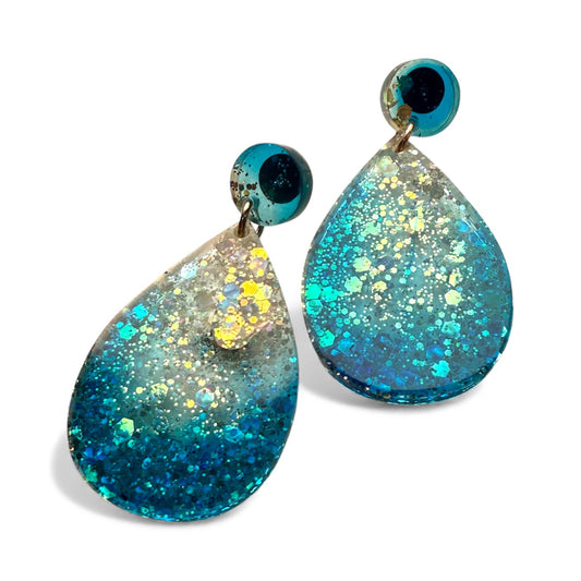 Ocean-blue resin drop earrings with layered shimmer and glossy texture.
