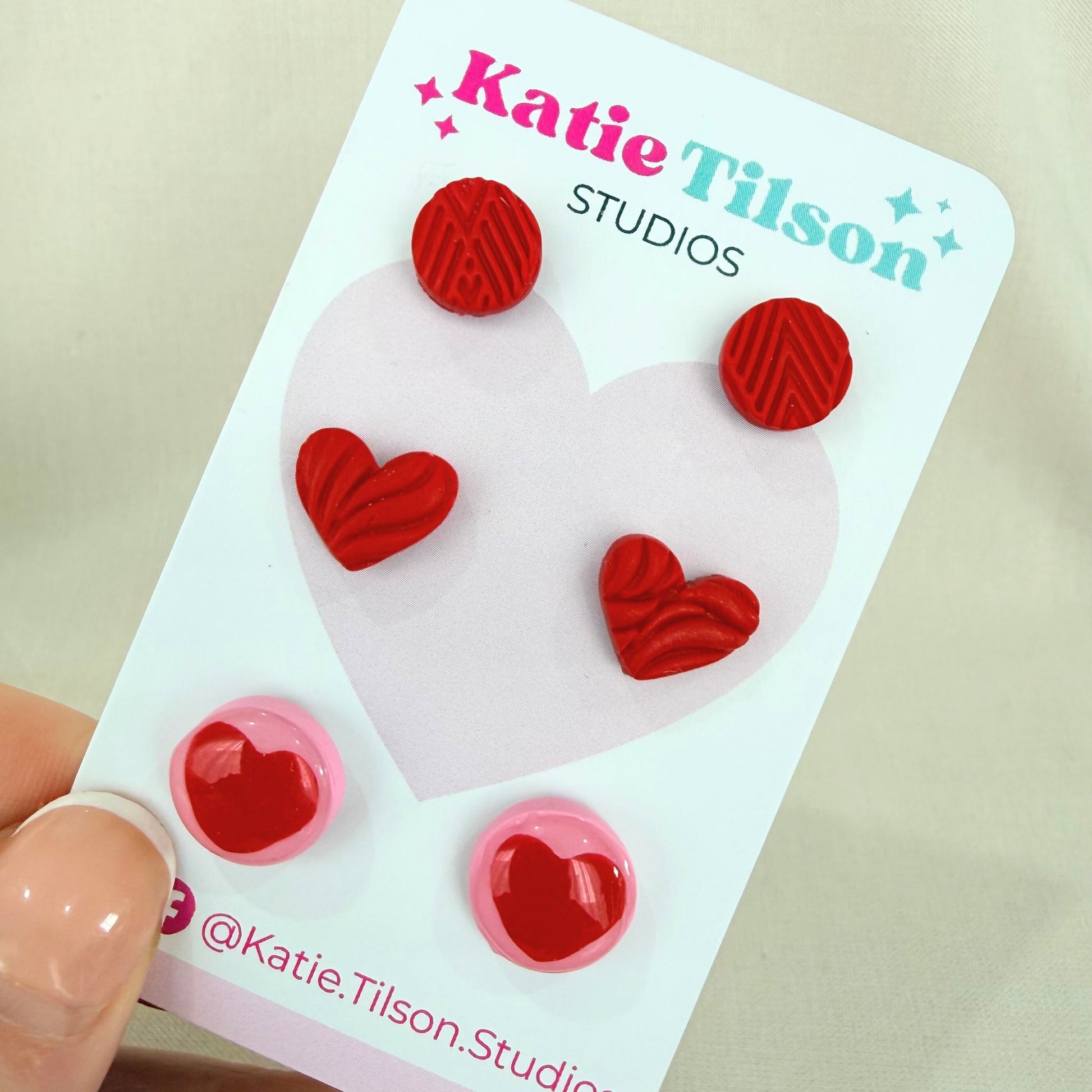 Trio of red Australian handmade stud earrings on a Katie Tilson Studios packaging with a beige background.