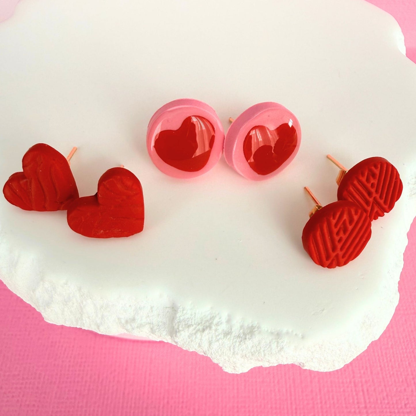 Cherry Crush Australian handmade stud earrings trio on a white stone with a pink background.