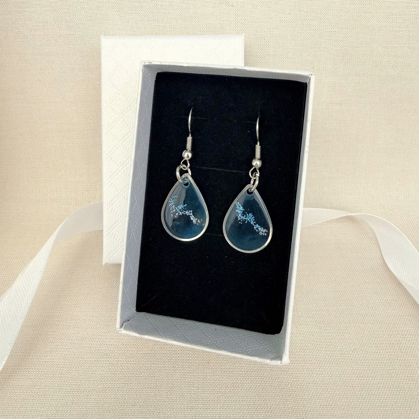 Coastal Glow handmade resin dangle earrings resting on black velvet insert in white gift box
