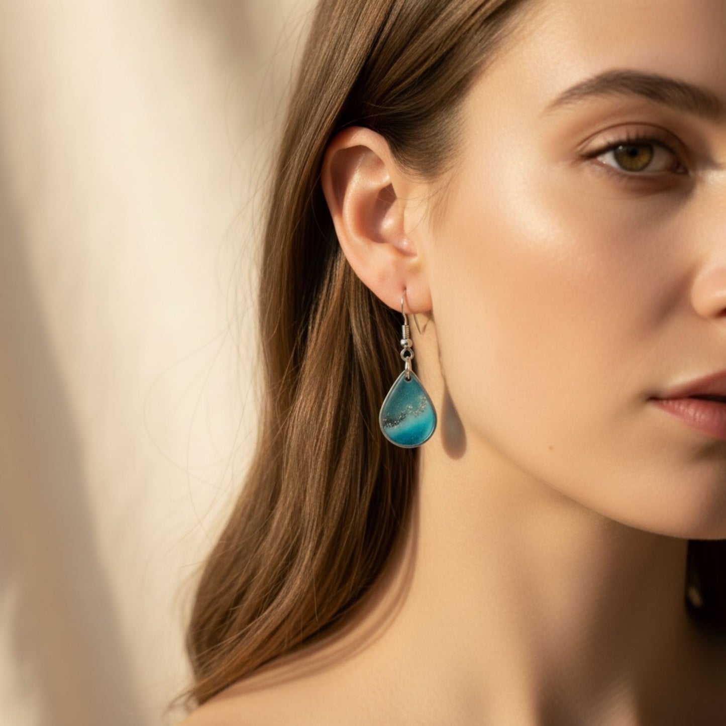 Woman wearing Coastal Glow Australian handmade earrings in coastal blue resin with soft shimmer by Katie Tilson Studios