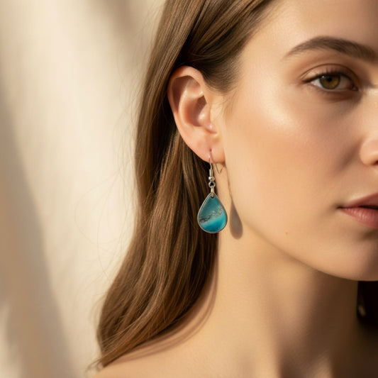 Woman wearing Coastal Glow Australian handmade earrings in coastal blue resin with soft shimmer by Katie Tilson Studios