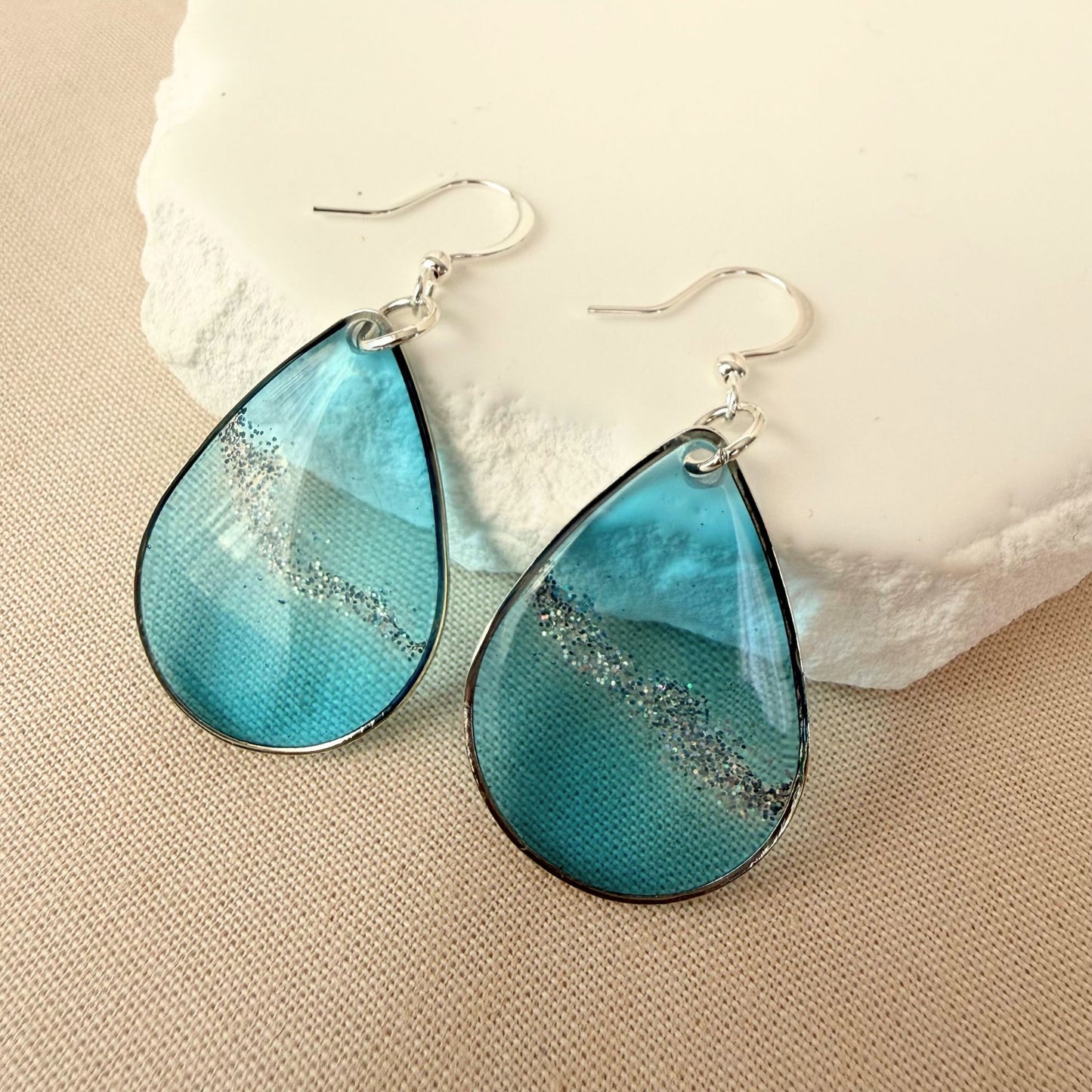 Australian handmade dangle earrings Coastal Glow in blue resin with subtle silver shimmer and silver toned earring hooks.