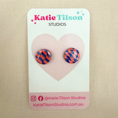 Colorful blue and coral checkered circular stud earrings on a Katie Tilson Studios card against a beige background.