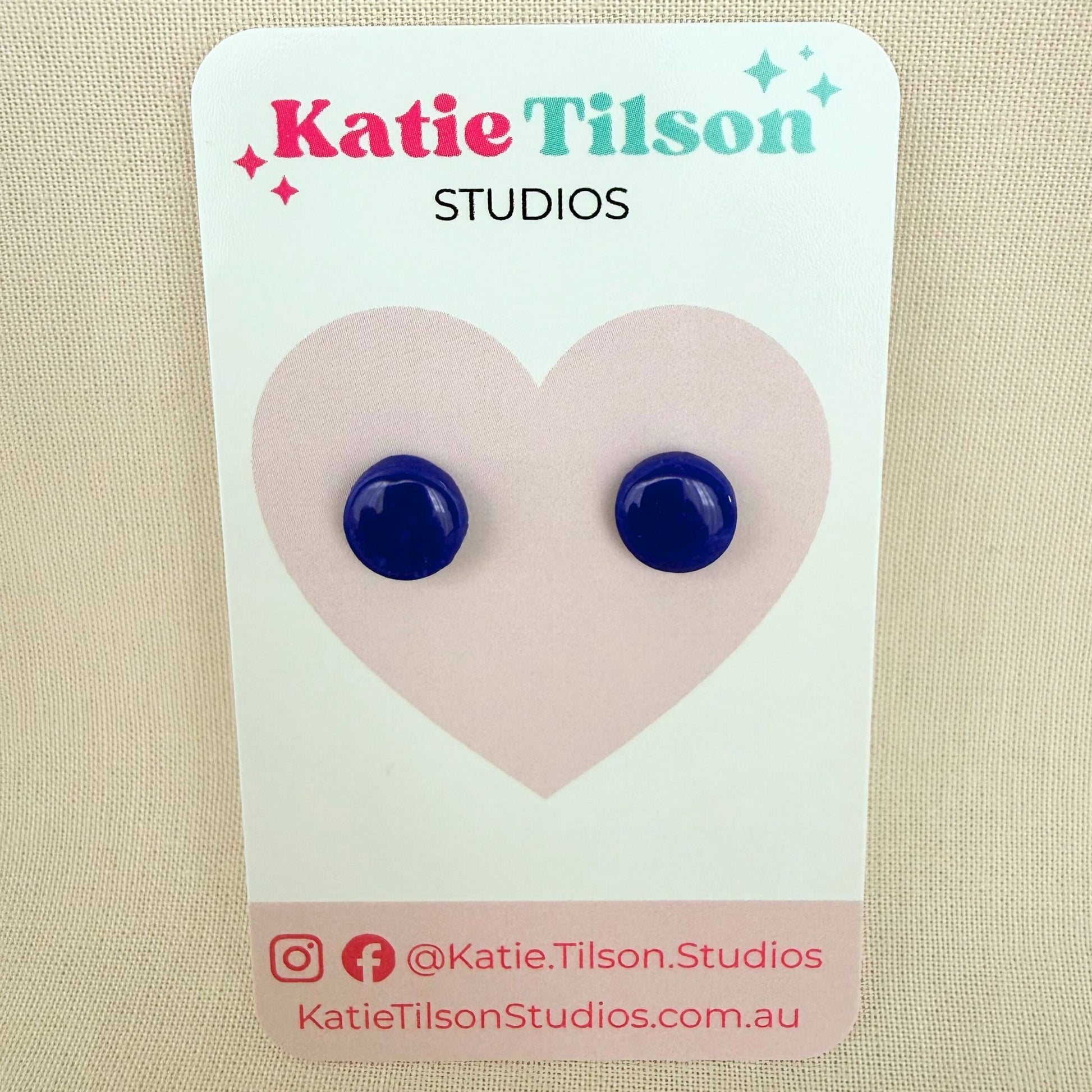 Cobalt blue circular stud earrings on a Katie Tilson Studios branded card with a beige background