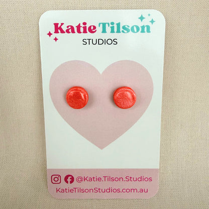 Coral colour round stud earrings on a Katie Tilson Studios branded earring card against a beige background.