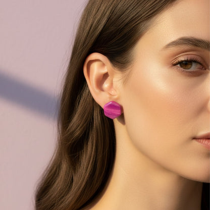 Close-up of a woman wearing pink and purple Australian handmade stud earrings with a blurred background.
