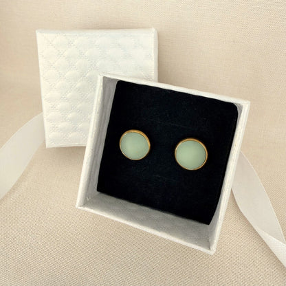 Pair of Australian handmade light eucalyptus green earrings with gold bezel in a white box on a beige background.