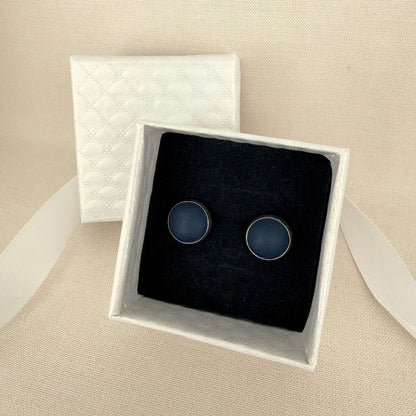 Pair of Australian handmade navy stud earrings with silver bezel in a white box on a beige background.