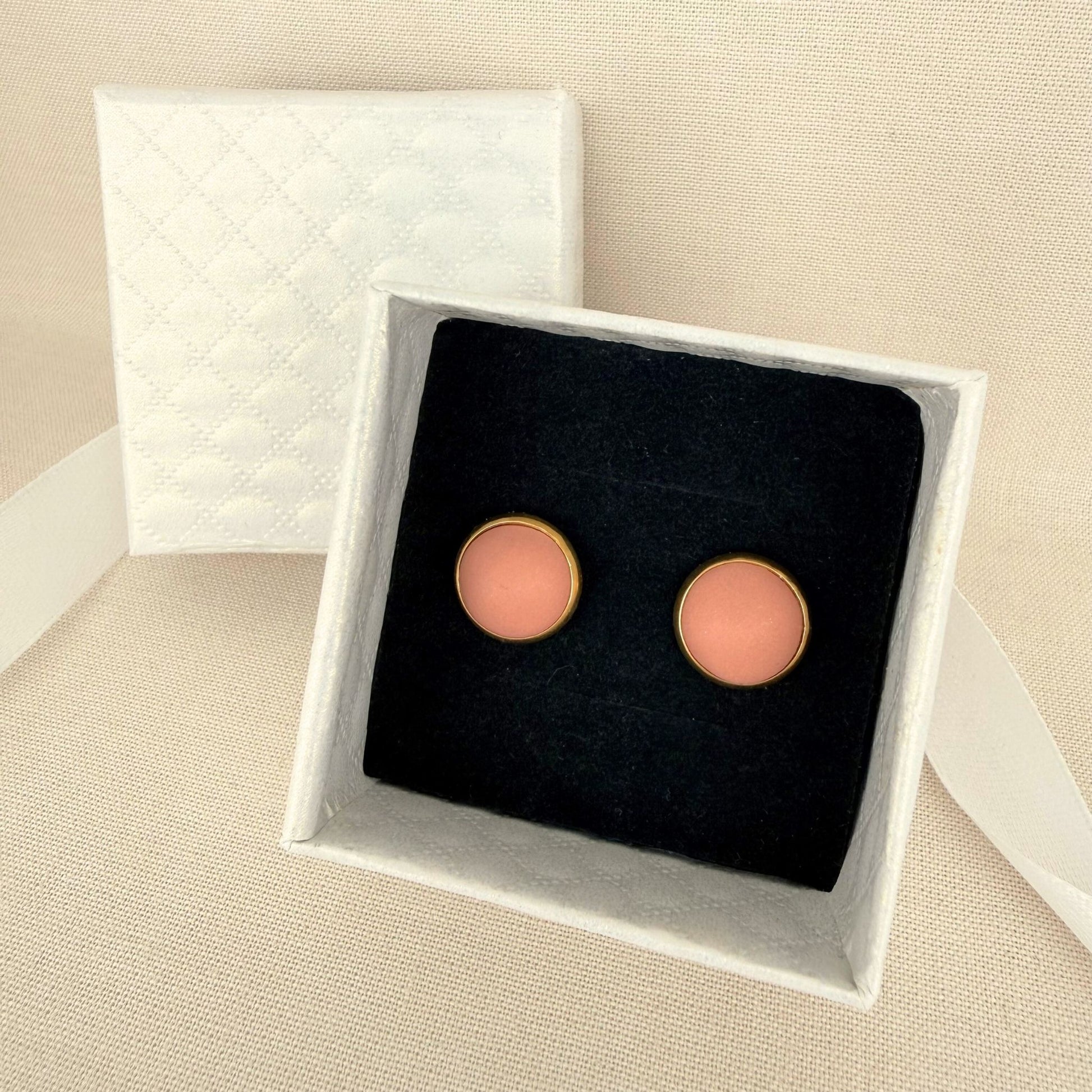 Pair of Australian handmade blush pink earrings with gold bezel in a white box on a beige background.