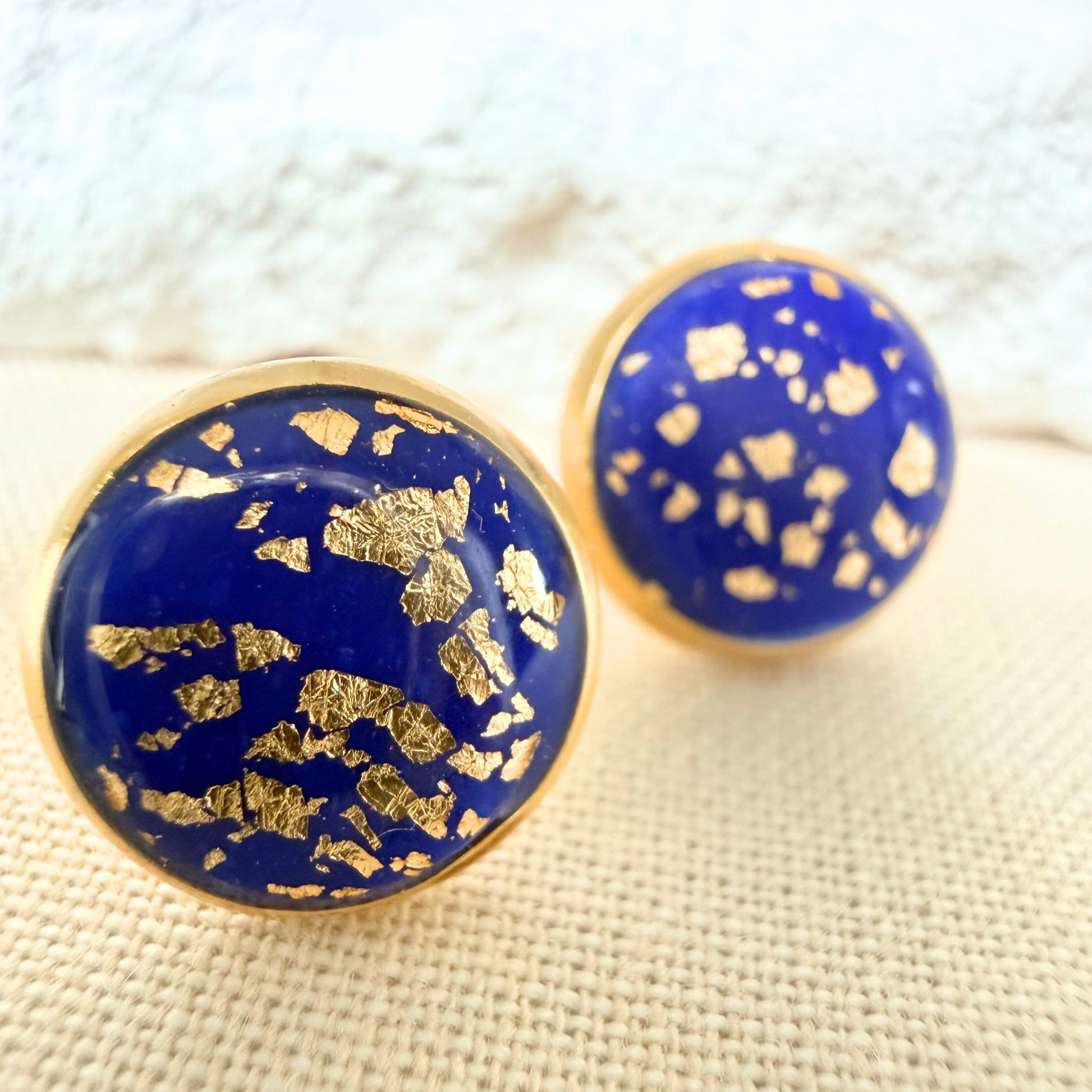 Close up of Good Vibes handmade stud earrings in cobalt colour with gold flecks and gold bezel.