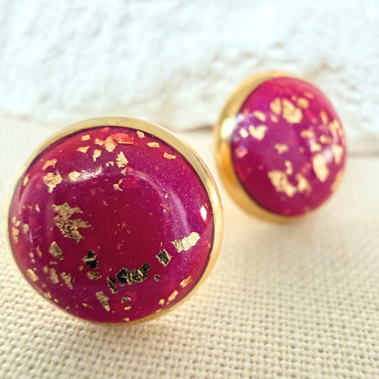 Close up of Good Vibes handmade stud earrings in magenta colour with gold flecks and gold bezel.