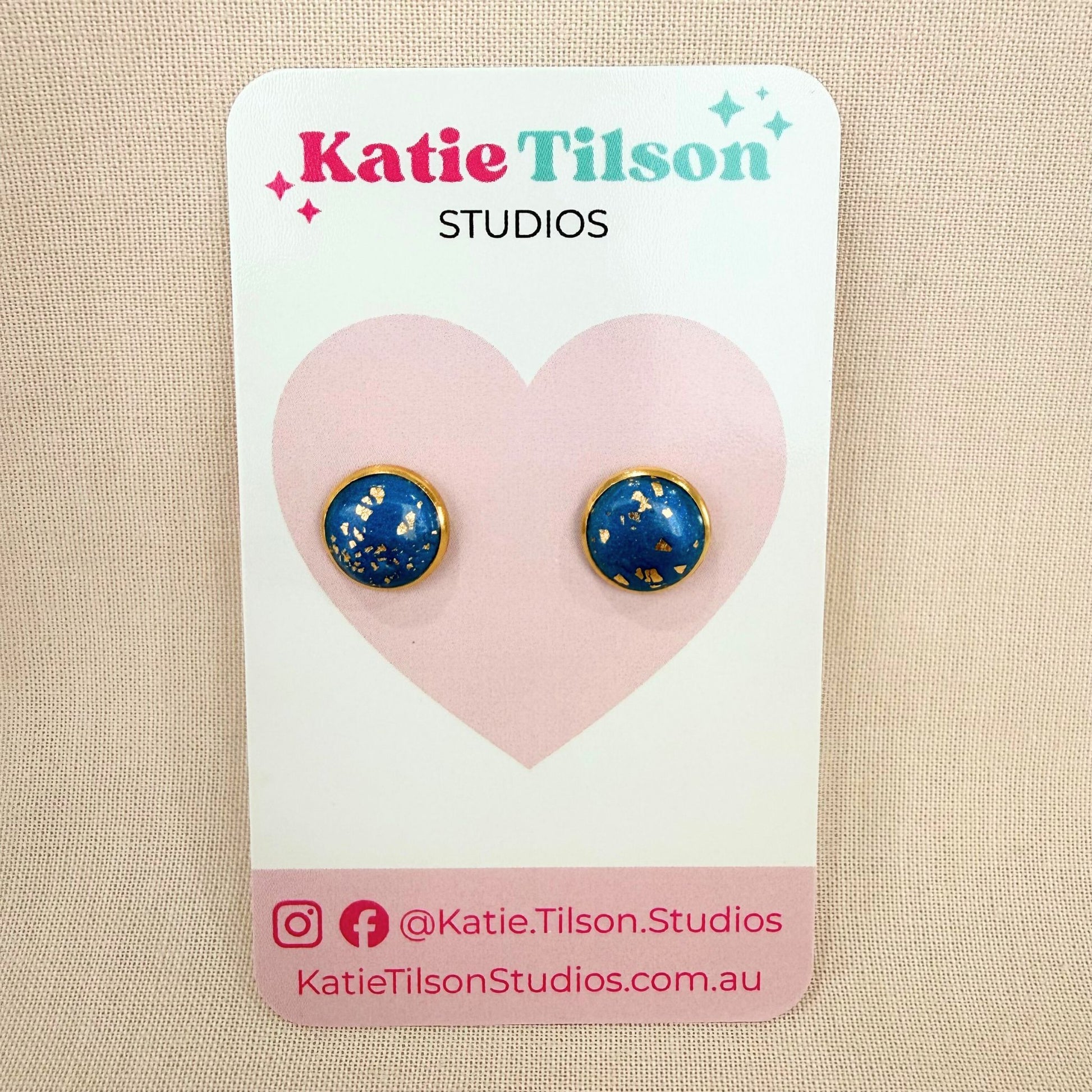 Teal stud earrings with gold accents on a Katie Tilson Studios branded card.