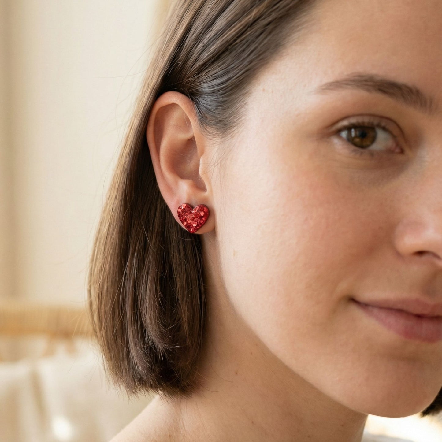 Close-up of a woman wearing red stud heart-shaped earrings.