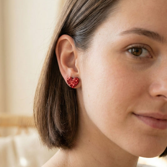 Close-up of a woman wearing red stud heart-shaped earrings.