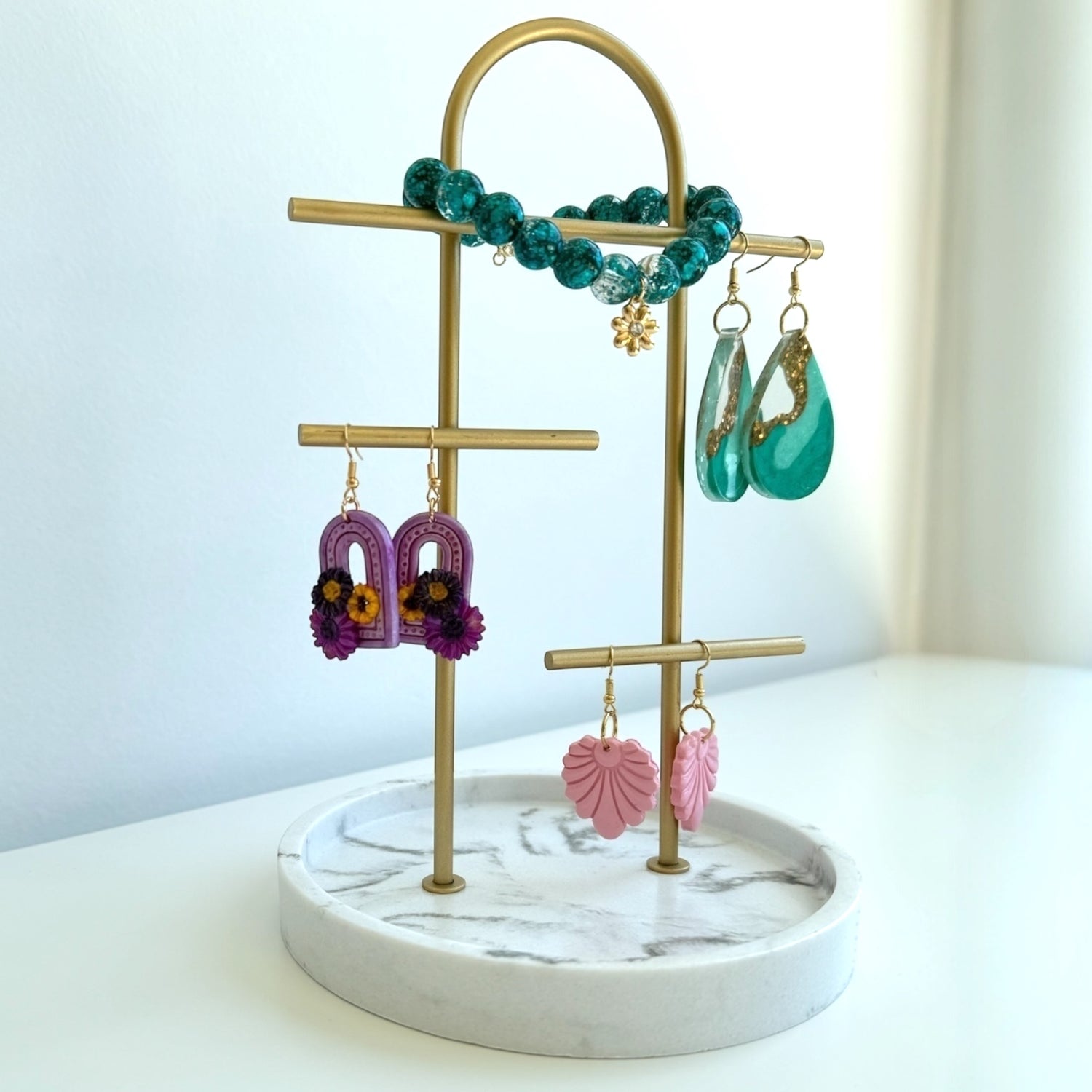 Jewellery stand featuring handmade earrings and a bracelet on a marble base