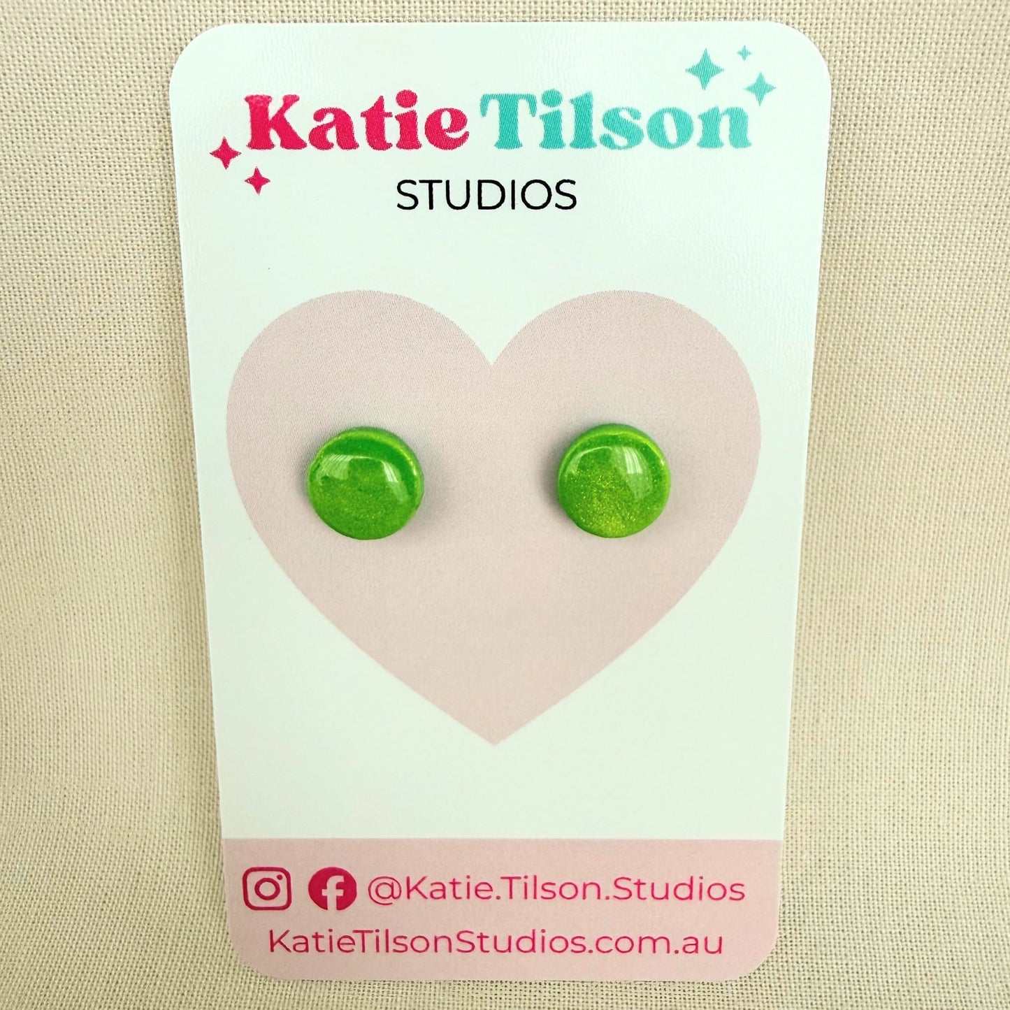 Lime green round stud earrings on a Katie Tilson Studios card against a beige background.