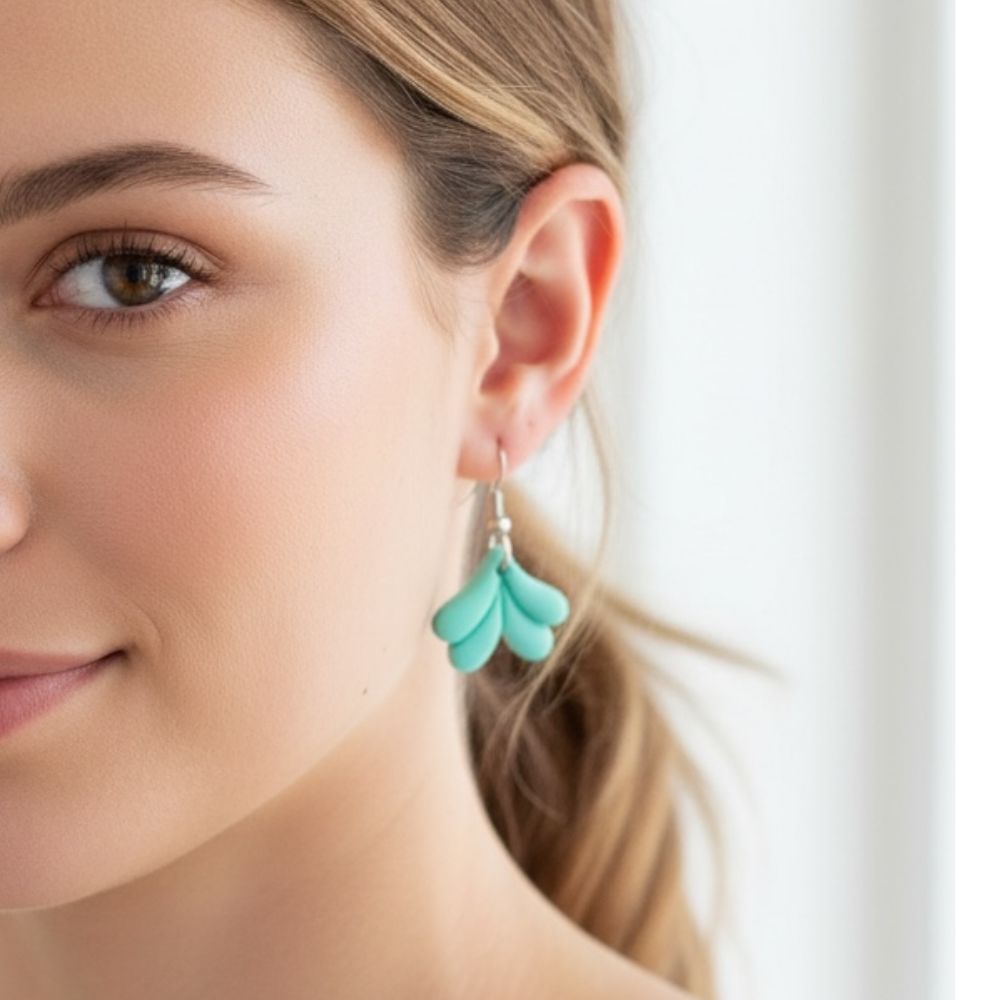 Close-up of a woman wearing turquoise Mermaid Tail dangle earrings with a blurred background.
