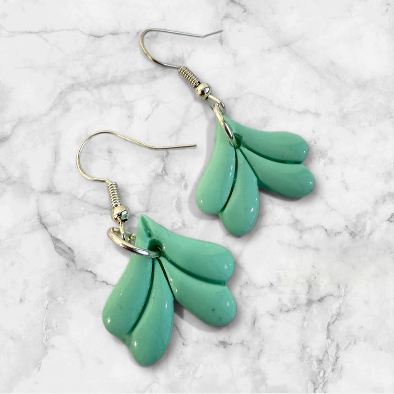 mermaid tail shaped polymer clay earrings in mint green on a marble background