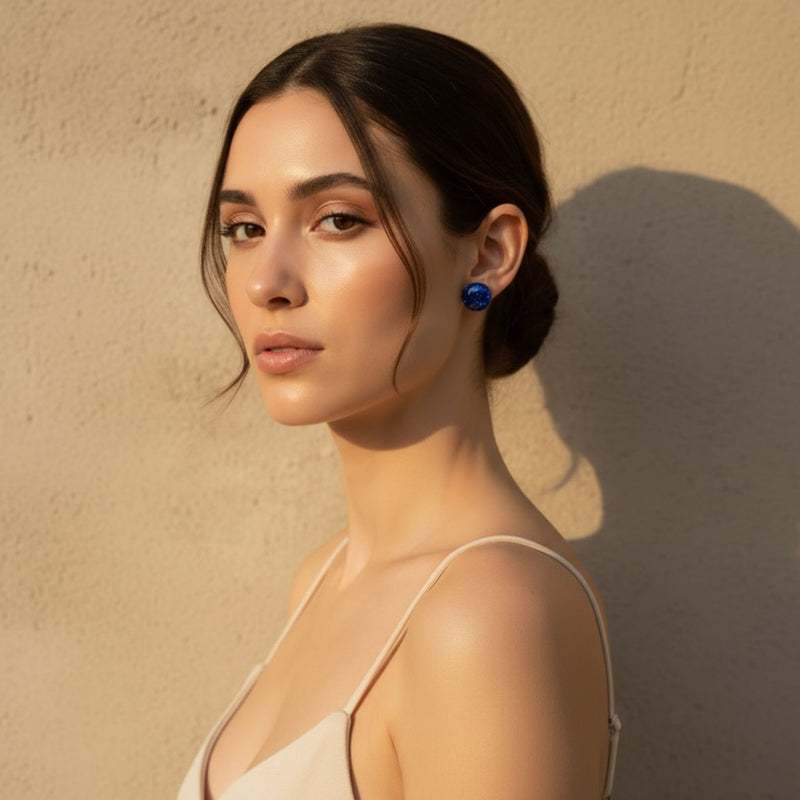 Woman wearing Australian handmade blue resin earrings standing against a beige wall.