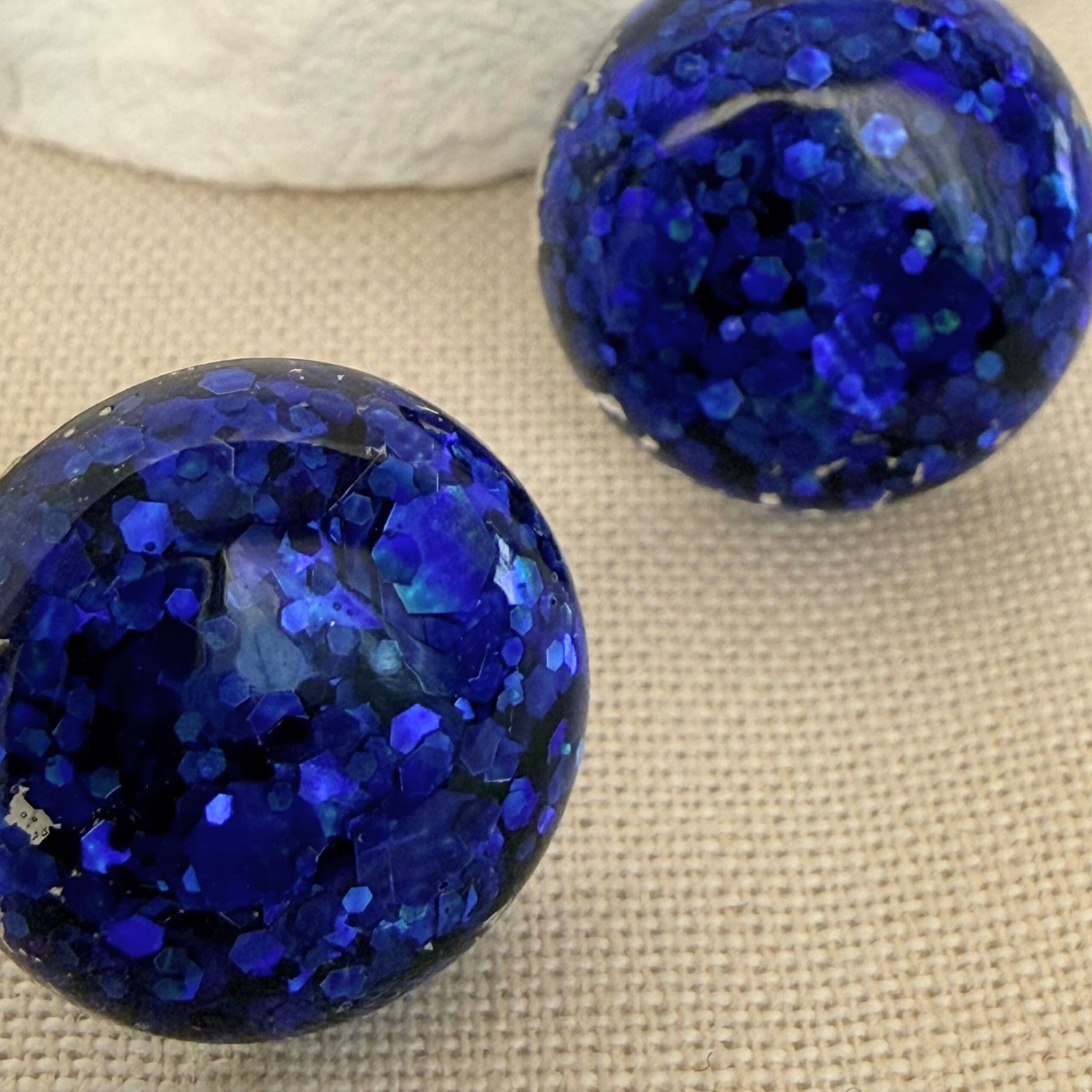 Close up of lightweight handmade stud earrings Midnight Glow in deep blue resin sparkle.