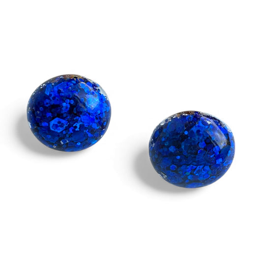 Deep blue glitter resin dome stud earrings with nickel-free gold hardware.