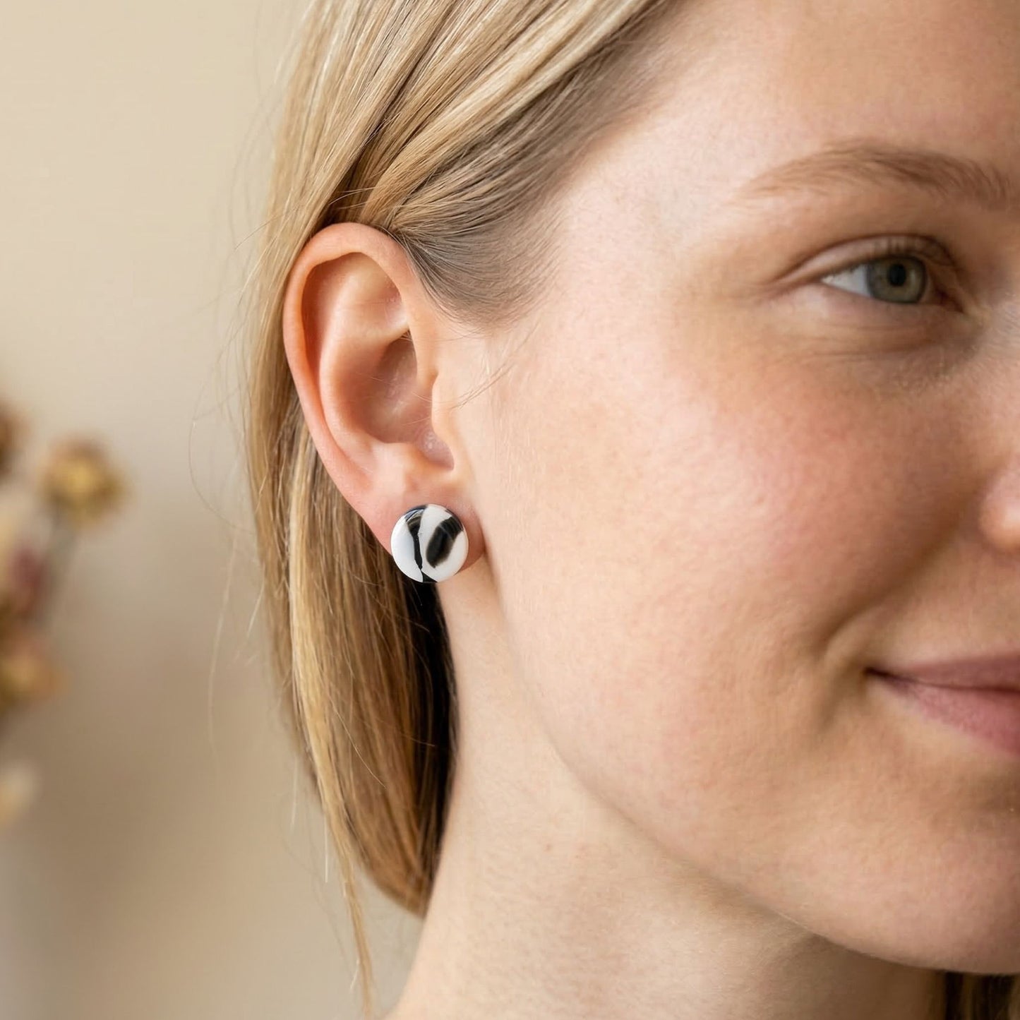 Close up of a woman wearing black and white patterned circular stud earrings.