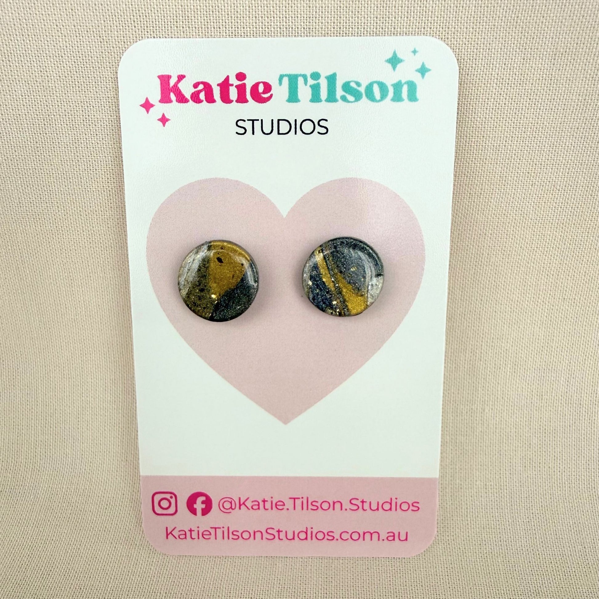 Gold and silver abstract design stud earrings on a Katie Tilson Studios card against a beige background.