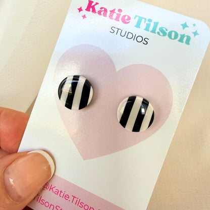 Black and white striped circular stud earrings on a Katie Tilson Studios card held by a hand.