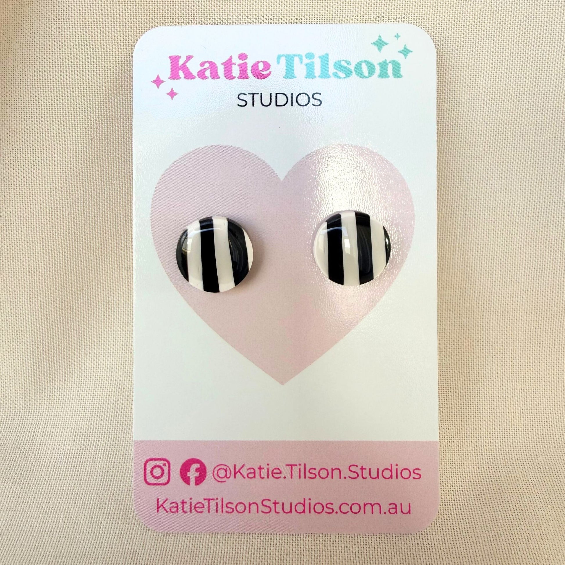 Black and white striped circular stud earrings on a Katie Tilson Studios card against a beige background.
