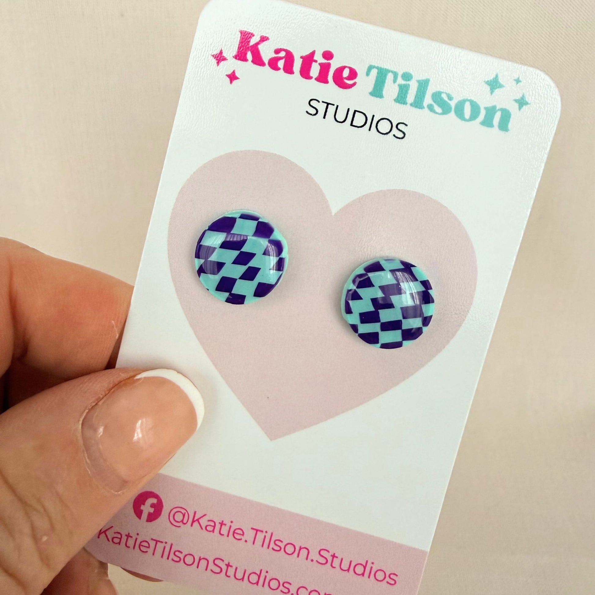 Mint and violet checkered stud earrings on a Katie Tilson Studios card held by a hand.