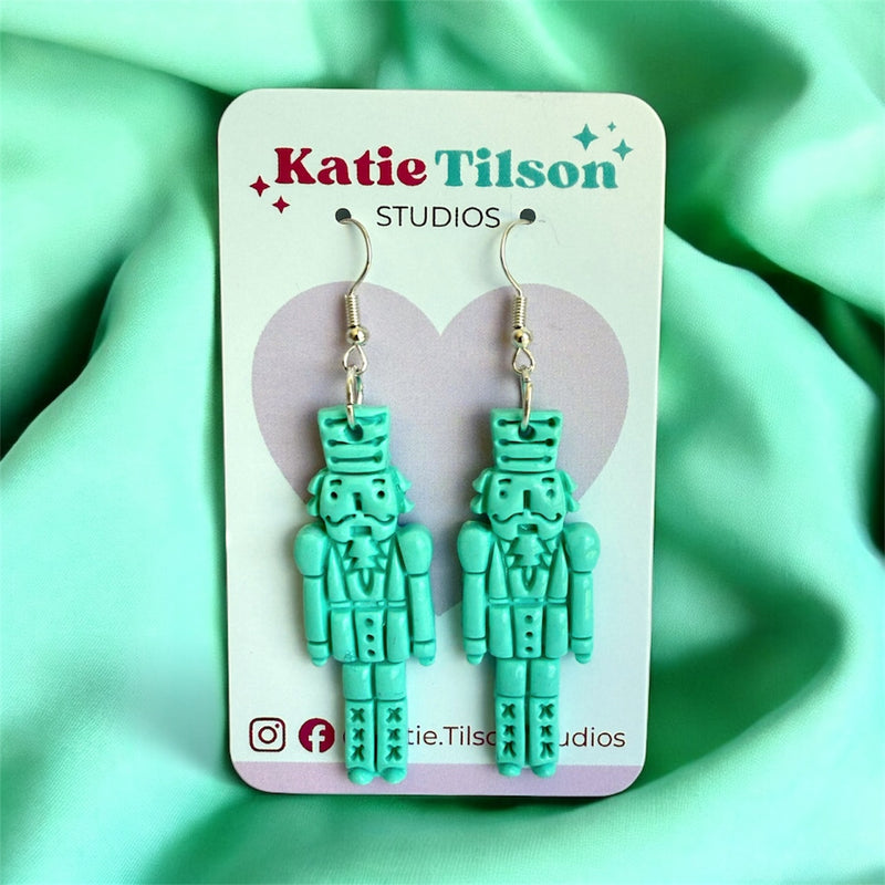 Mint green nutcracker earrings on a Katie Tilson Studios card with a heart design.