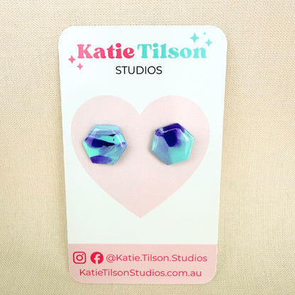 Violet and mint geometric stud earrings on a Katie Tilson Studios card against a beige background.