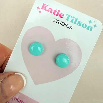 Mint colour circular stud earrings on a Katie Tilson Studios card held by a hand.