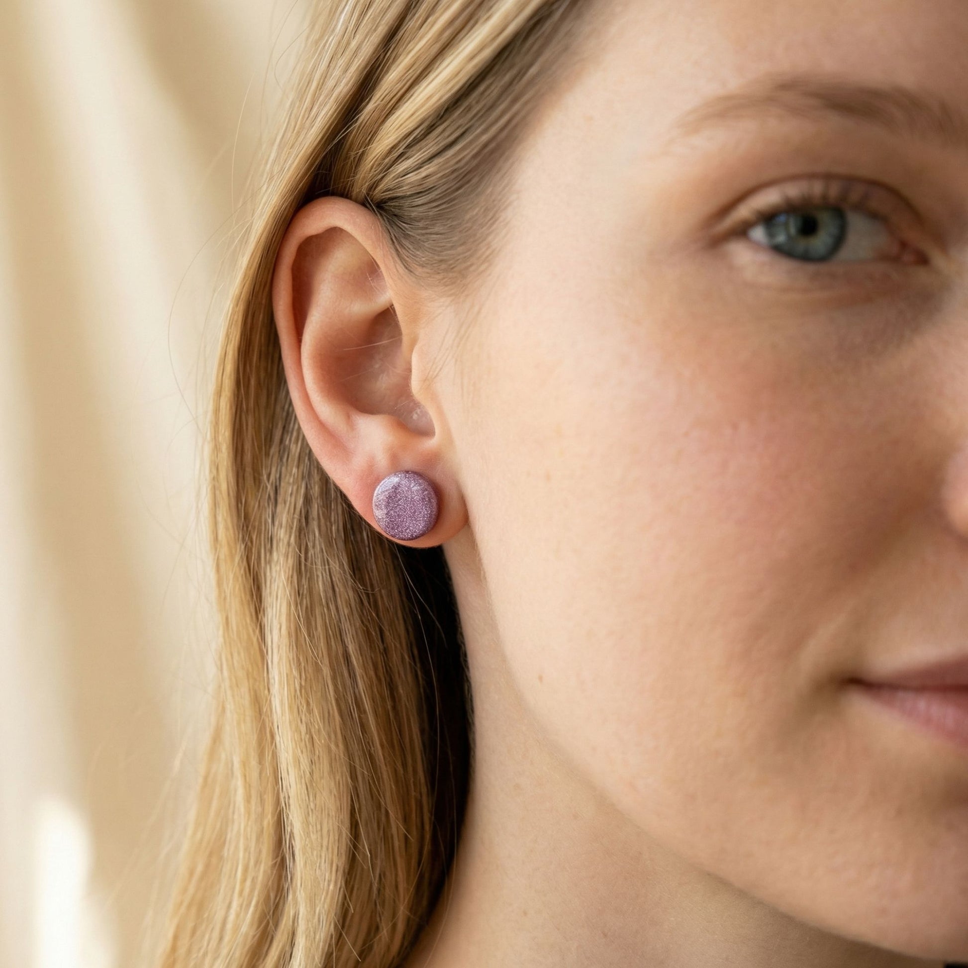 Close-up of a woman wearing mulberry stud earrings with a neutral background
