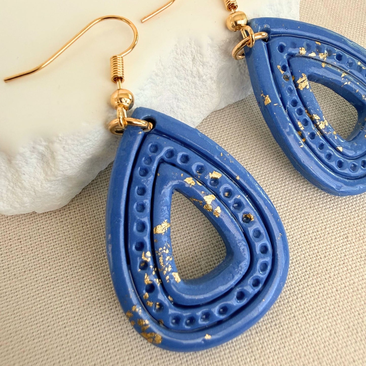 Close up of lightweight handmade dangle earrings Ocean Gleam Teardrops in blue with gold leaf details.