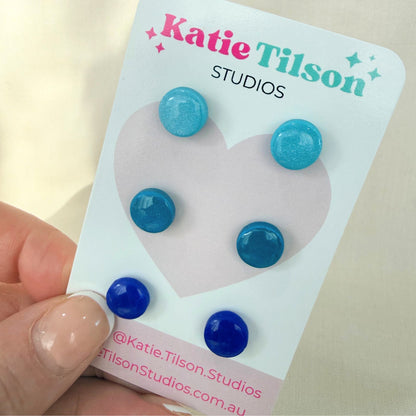 Ocean blue earring trio on a Katie Tilson Studios packaging with a hand holding it.