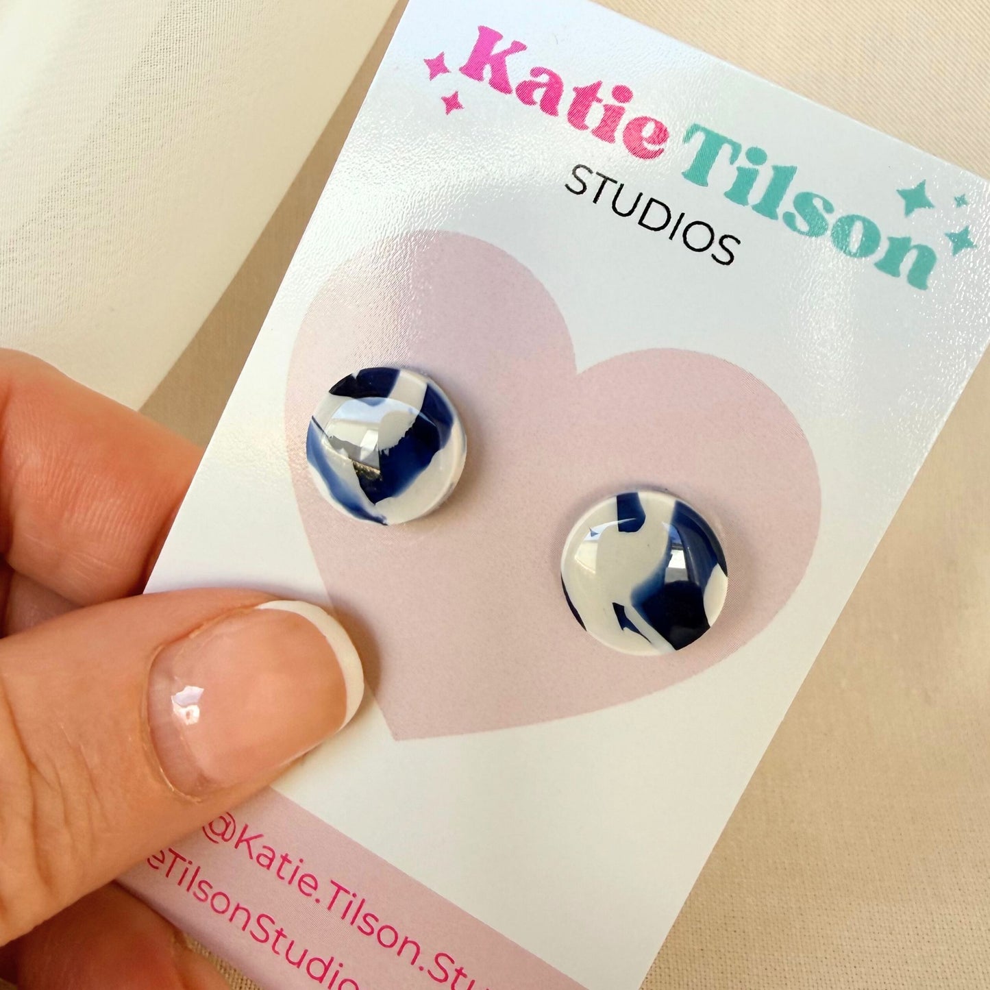 Pair of blue and white swirled design stud earrings held on a Katie Tilson Studios card.